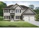 Two-story home with a stone facade, dark shutters, and a two-car garage, surrounded by a green lawn and landscaping at 3264 Lions Ruby Ln, Atlanta, GA 30349