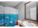 Bright bathroom featuring colorful ocean-themed shower curtain, and single sink vanity with a framed mirror at 950 Besse Way, Locust Grove, GA 30248