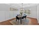 Elegant dining room features wainscoting, a modern chandelier, and a large window overlooking the front yard at 4720 Cooling Water Sw Cir, Powder Springs, GA 30127