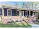 View of the front porch of the house with black vertical siding and brick foundation and steps at 5925 Old Bill Cook Rd, South Fulton, GA 30349