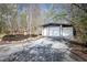Detached three-car garage with white doors, surrounded by trees and a landscape rock garden at 5925 Old Bill Cook Rd, South Fulton, GA 30349