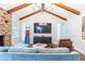 An open concept living room with a TV, brick fireplace, wooden beams and modern furnishings at 5925 Old Bill Cook Rd, South Fulton, GA 30349