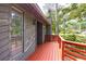 View of the covered front porch with weathered wood and a red railing at 633 Iris Rd, Pine Lake, GA 30072