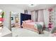 Vibrant bedroom featuring a pink bed, vanity mirror with lights, and decor on shelves at 9744 Musket Ridge Cir, Jonesboro, GA 30238