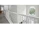 Bright hallway with white railing, neutral walls, and a view of an arched window and a bedroom entry at 9744 Musket Ridge Cir, Jonesboro, GA 30238