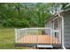 Side of cottage with wooden deck, air conditioning unit, grassy lawn and mature trees at 1786 Richard Ne Rd, Conyers, GA 30012