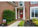 Close-up of front entrance showing red door with white trim, charming landscaping, and brick facade at 2002 Fairbrook Ln, Woodstock, GA 30189