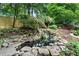 Backyard view of a stacked stone waterfall with lush landscaping and mature trees at 3106 Soldier Trl, Marietta, GA 30068
