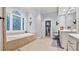 Bathroom featuring tile flooring, soaking tub under decorative window, and built-in vanity at 5560 Stoneleigh Dr, Suwanee, GA 30024
