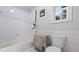 Bright, all-white bathroom featuring tiled walls, a bathtub, and a window for natural light at 5560 Stoneleigh Dr, Suwanee, GA 30024
