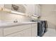 A laundry room with washer, dryer, sink, white cabinets, and overhead lighting at 5560 Stoneleigh Dr, Suwanee, GA 30024