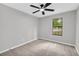 A bright bedroom featuring neutral walls, carpet, a ceiling fan, and a window offering natural light at 1829 Herringbone Holw, Lithonia, GA 30058