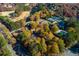 Scenic aerial view of community with golf course, tennis courts, and walking bridge amidst colorful trees at 5010 Winding Hills Ln, Woodstock, GA 30189