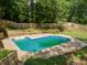 An in-ground pool with a concrete deck, surrounded by a wooden fence and lush greenery at 51 Queen Anne Se Dr, Mableton, GA 30126