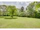 Lush green backyard with mature trees and a large open lawn at 203 Leigh Dr, Ellenwood, GA 30294