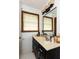 Bright bathroom with a beige vanity sink, dark wooden cabinets, window, and a framed mirror at 203 Leigh Dr, Ellenwood, GA 30294