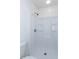 A well lit walk-in shower stall features a white shower surround, chrome showerhead and fixtures at 203 Leigh Dr, Ellenwood, GA 30294