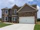 Two-story home with brick facade and a two car garage, as well as manicured landscaping at 306 Rodeo Dr, Auburn, GA 30102