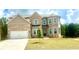 Charming brick home with a two-car garage, green lawn, and blue skies at 306 Rodeo Dr, Auburn, GA 30102