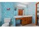 A bathroom with blue floral wallpaper, and a wood vanity with white countertop sink at 110 The Farm Rd, Mcdonough, GA 30252