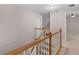 Hallway with wood and white banister and neutral carpeting leading to stairway in neutral color scheme at 445 Royal St, Mcdonough, GA 30253