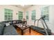 Bright sitting room is furnished with a black leather sectional, treadmill, and natural lighting at 2623 Grapevine Cir # 602, Cumming, GA 30041