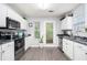 Well-lit kitchen with stainless steel appliances, white cabinets, and a door to the exterior at 5527 Jerome Rd, College Park, GA 30349