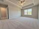 Well-lit main bedroom showcasing neutral paint, tray ceiling, carpet, and adjacent bathroom at 1277 Fern Ridge Ct # 22, Norcross, GA 30093