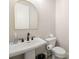 Chic powder room featuring a pedestal sink, arched mirror, and modern fixtures for a touch of elegance at 1358 Pavilion Se Ct, Atlanta, GA 30316