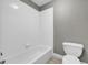 White tiled bathtub with a tiled wall going up and toilet seat beside tub at 3641 Carriage Glen Way, Dacula, GA 30019