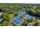 Aerial view of well-maintained blue and green tennis courts surrounded by lush trees and landscaping at 3641 Carriage Glen Way, Dacula, GA 30019