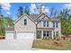 Stunning two-story home showcasing stone facade, manicured lawn, and a three car attached garage at 6944 Melody Ridge Rd, Buford, GA 30518
