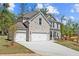 Beautiful stone fronted home with a wide driveway and three car garage, surrounded by lush trees at 6944 Melody Ridge Rd, Buford, GA 30518