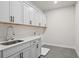 Well-lit laundry room with white cabinets, gray countertops, and gray tile flooring at 6944 Melody Ridge Rd, Buford, GA 30518