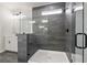 Close up of a modern shower featuring gray tile walls, glass enclosure and black hardware at 6944 Melody Ridge Rd, Buford, GA 30518