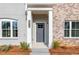 A covered front porch with a gray door and white columns gives this home an inviting entrance at 4810 Floydwood Ln, Mableton, GA 30126