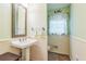 Charming powder room with pedestal sink, wainscoting, and decorative mirror, adding a touch of elegance to the home at 7310 Ne Wynhill Ne Dr, Atlanta, GA 30328