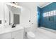 Modern bathroom with blue tiled shower, white vanity, and a window allowing natural light at 2407 Boulder Se Rd, Atlanta, GA 30316