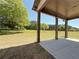 Covered back porch with a large backyard and green trees on a sunny day at 3132 Rosebud Rd, Loganville, GA 30052