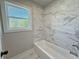 Window view from bathtub featuring marble-tiled walls and flooring at 3132 Rosebud Rd, Loganville, GA 30052