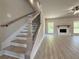 Open-concept room boasts fireplace, hardwood floors, neutral colors, and staircase to 2nd floor at 3132 Rosebud Rd, Loganville, GA 30052