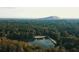 Beautiful aerial view of the property's lake, forests, and the stunning mountain view in the distance at 4807 Kenilworth Dr, Stone Mountain, GA 30083