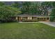 Charming brick home with a well-manicured lawn, mature trees, and covered parking at 4807 Kenilworth Dr, Stone Mountain, GA 30083