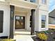 Inviting front entrance with dark stained wooden pillars and double doors on a white brick home at 3154 Rosebud Rd, Loganville, GA 30052