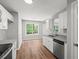 Galley kitchen featuring white cabinets, granite counters, stainless steel dishwasher, and wood flooring at 102 Pine Bark Dr, Villa Rica, GA 30180