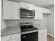 Bright kitchen with white cabinetry, stainless steel microwave and oven, and granite countertops at 102 Pine Bark Dr, Villa Rica, GA 30180