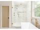 Bright bathroom featuring a modern tub, a glass-enclosed shower, elegant gold fixtures, and a large window at 253 Rockyford Ne Rd, Atlanta, GA 30317