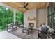 Inviting covered patio with a cozy fireplace, stylish seating, and a scenic view of lush greenery at 253 Rockyford Ne Rd, Atlanta, GA 30317
