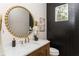 Stylish powder room with a gold mirror, modern vanity, and sleek black tiled accent wall at 253 Rockyford Ne Rd, Atlanta, GA 30317