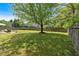 Large backyard with a well-maintained lawn, mature trees, and a wooden fence at 3477 Seneca Farm Dr, Buford, GA 30519